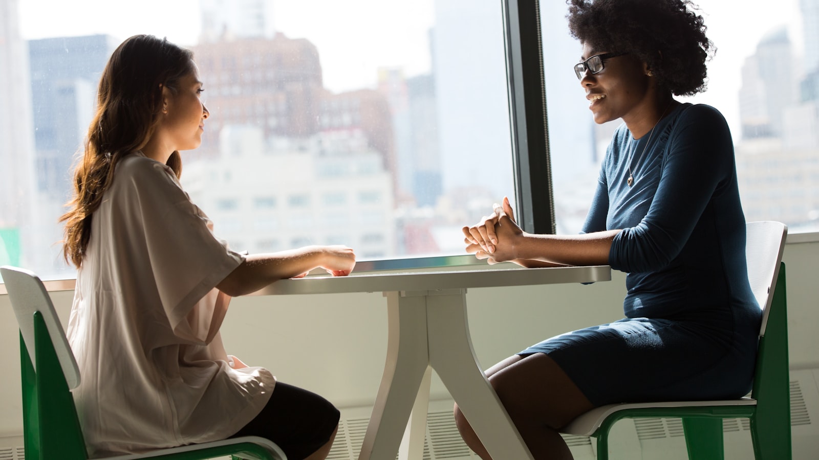 A real estate agent meeting a client across a table with a city skyline in the background