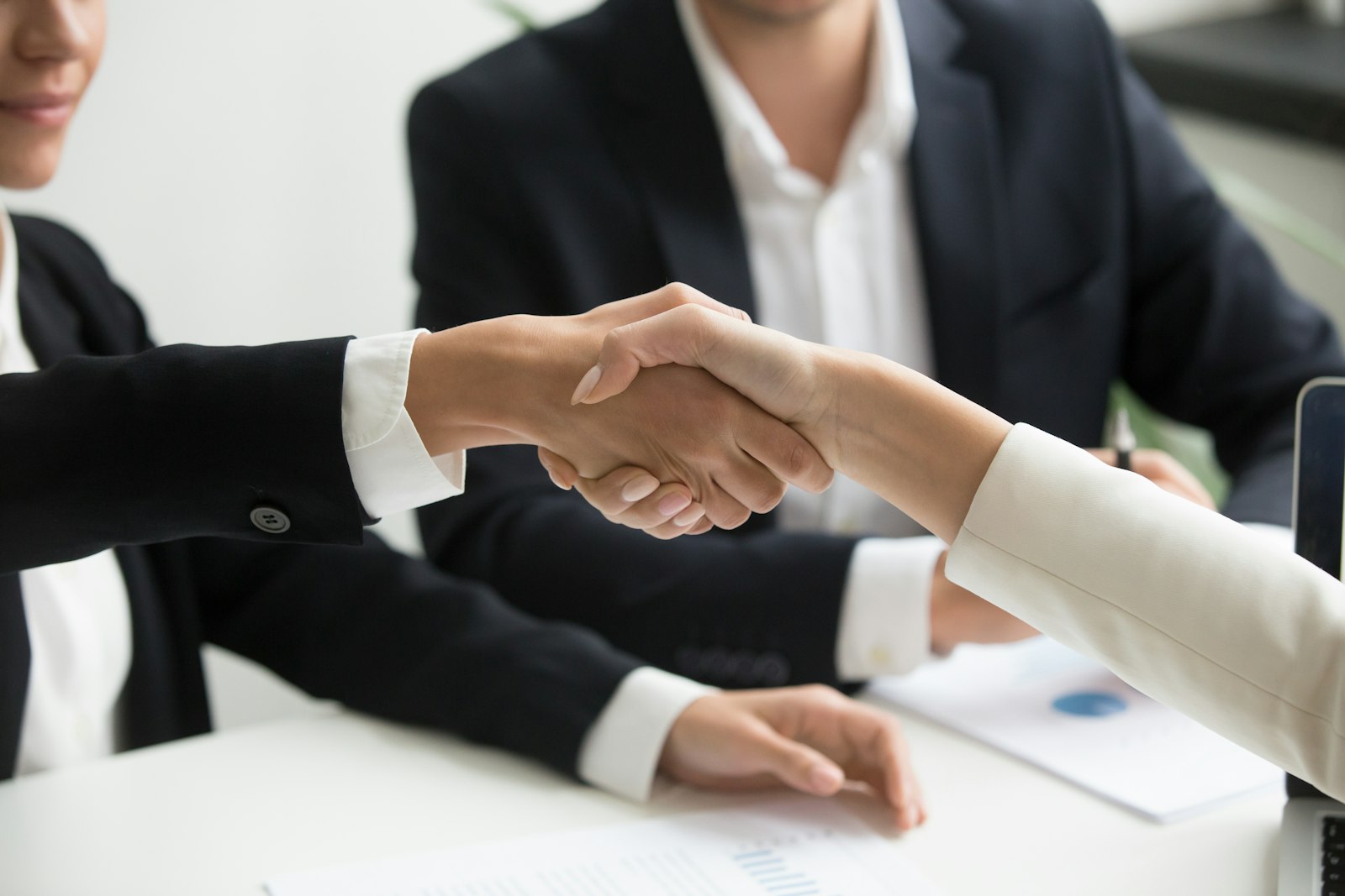 Two real estate professionals shaking hands after closing a deal in a Dubai brokerage office