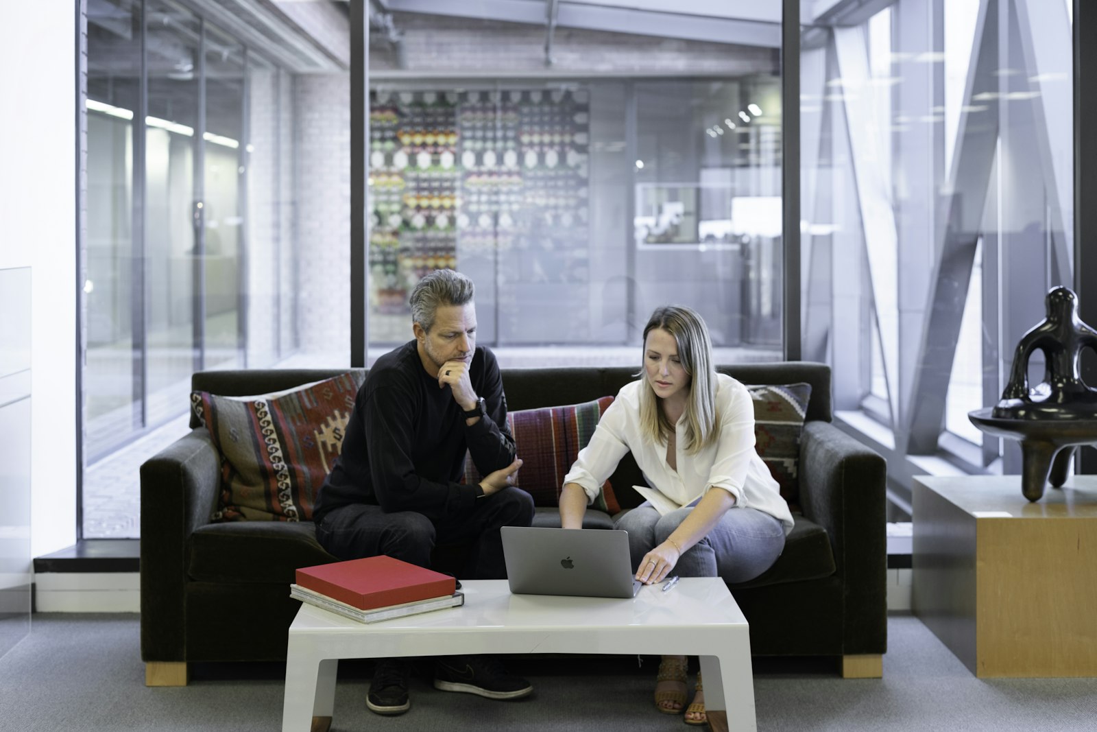 Two real estate professionals reviewing their CRM together on a laptop in a modern office