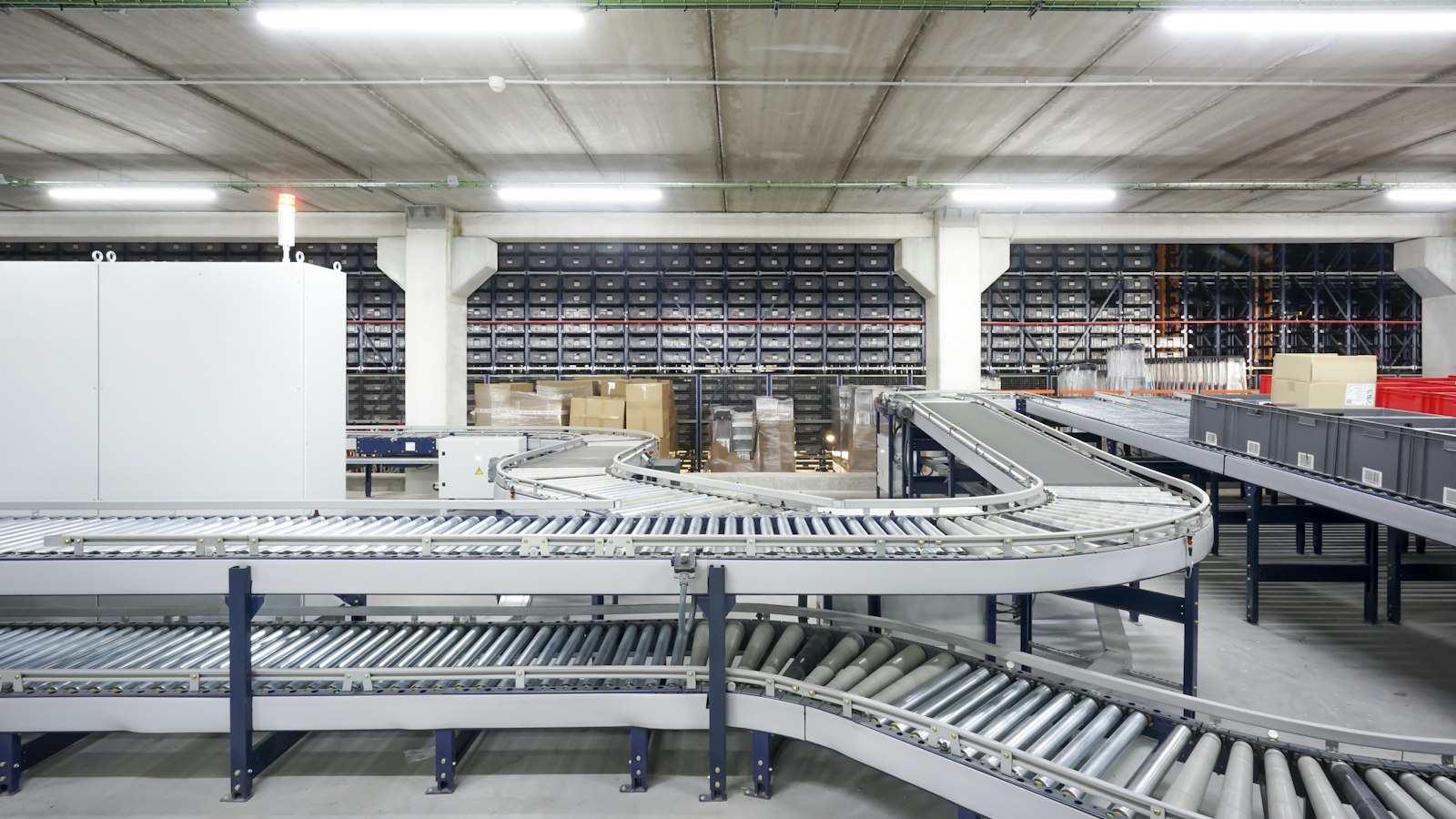 An empty automated warehouse conveyor system curving between storage racks, running without an operator in sight